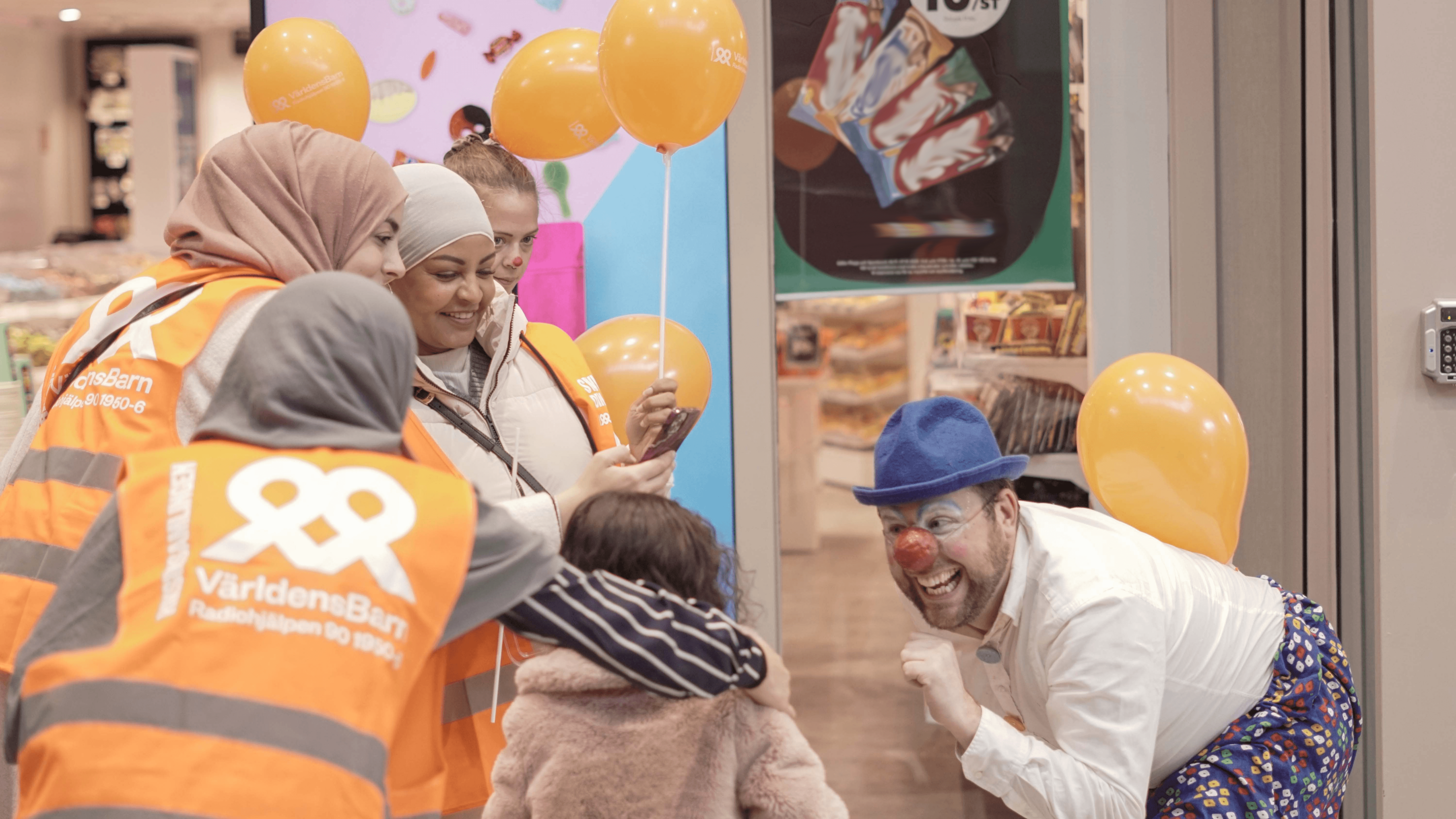 Barn, clown och kvinnor som är engagerade för Världens Barn