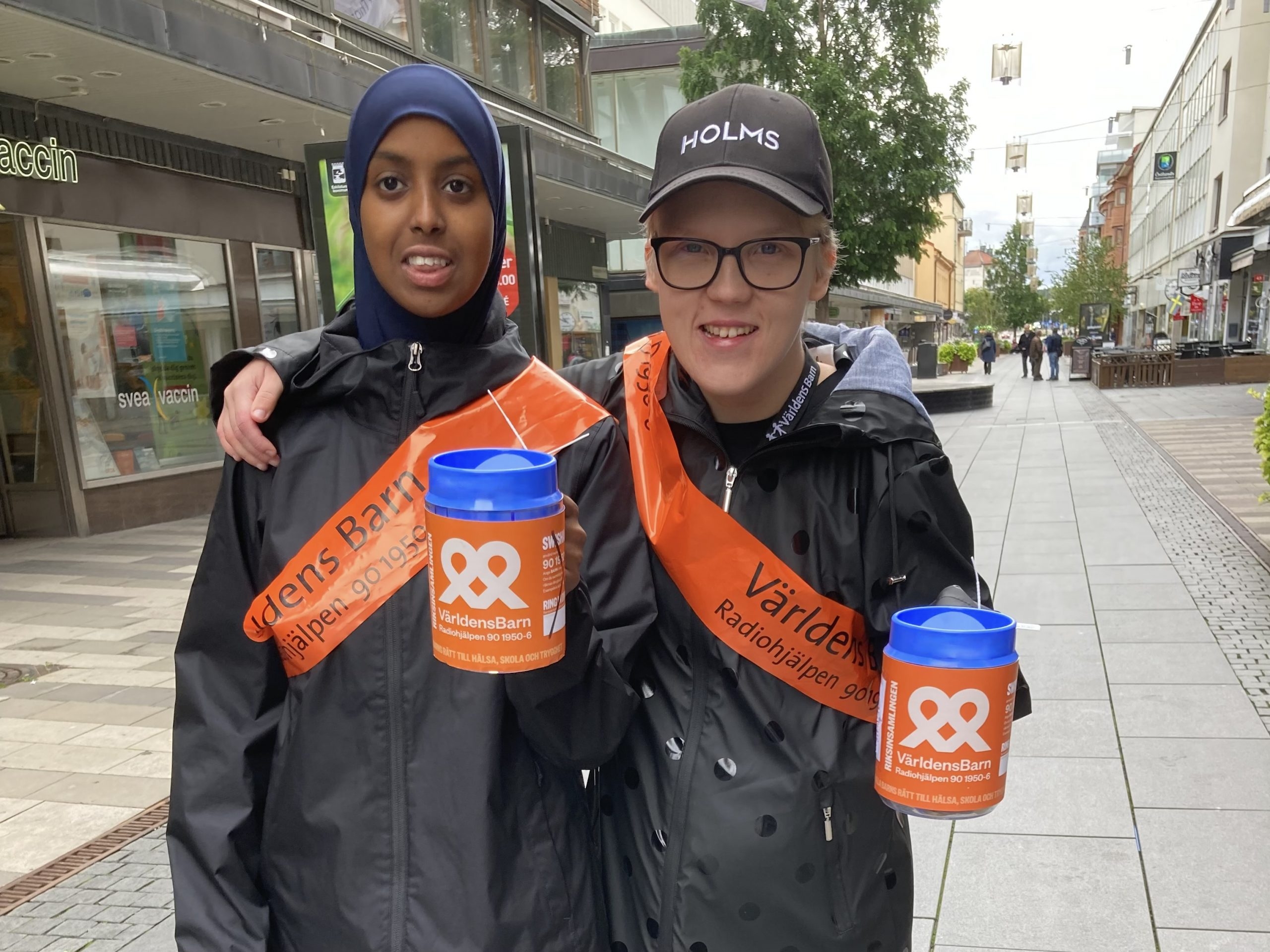 Två leende ungdomar som håller i insamlingsbössor