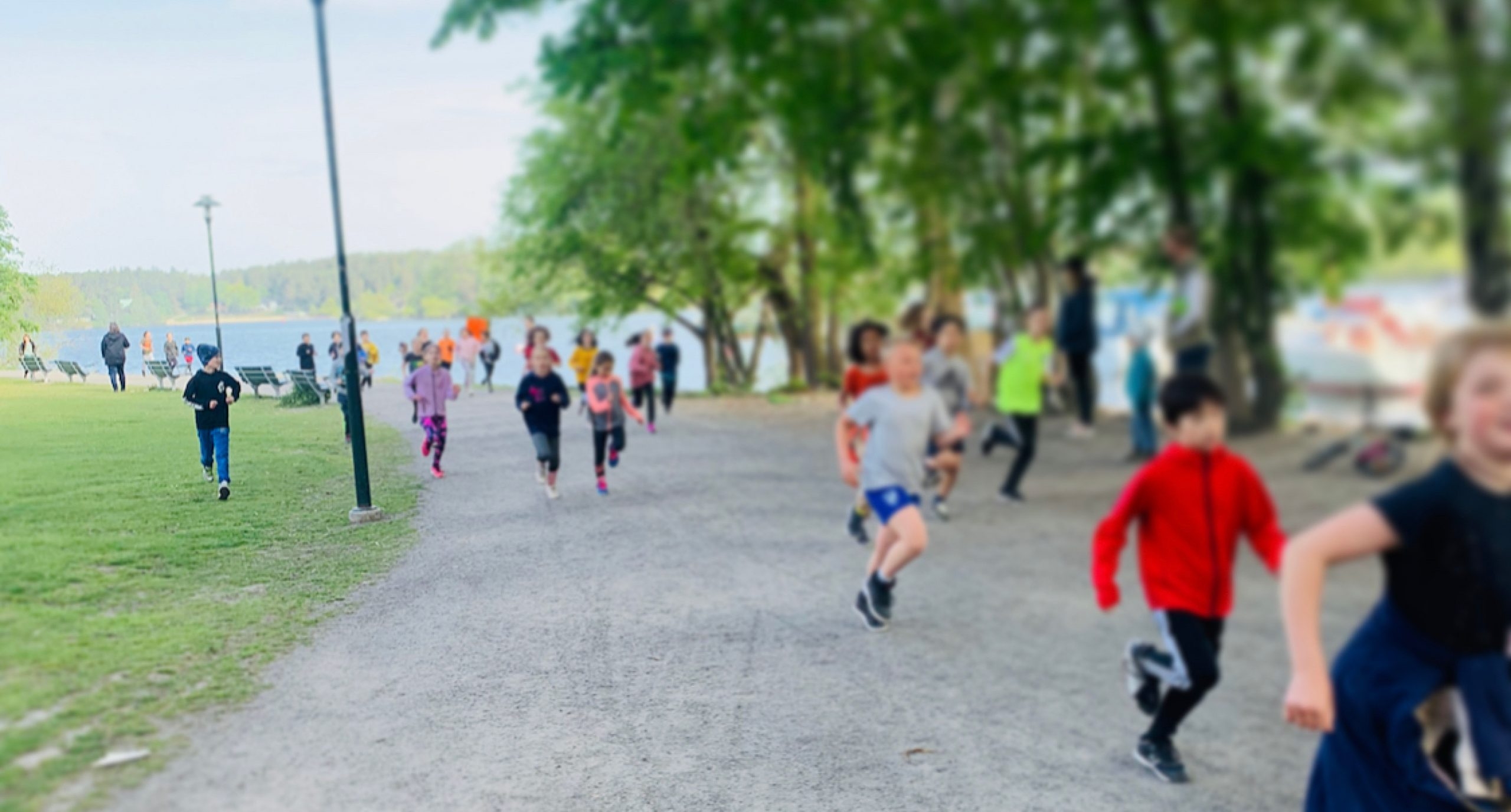 Barn springer på grusväg vid en sjö